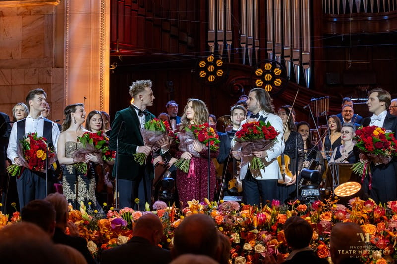 wszyscy soliści i dyrygent na scenie z kwiatami